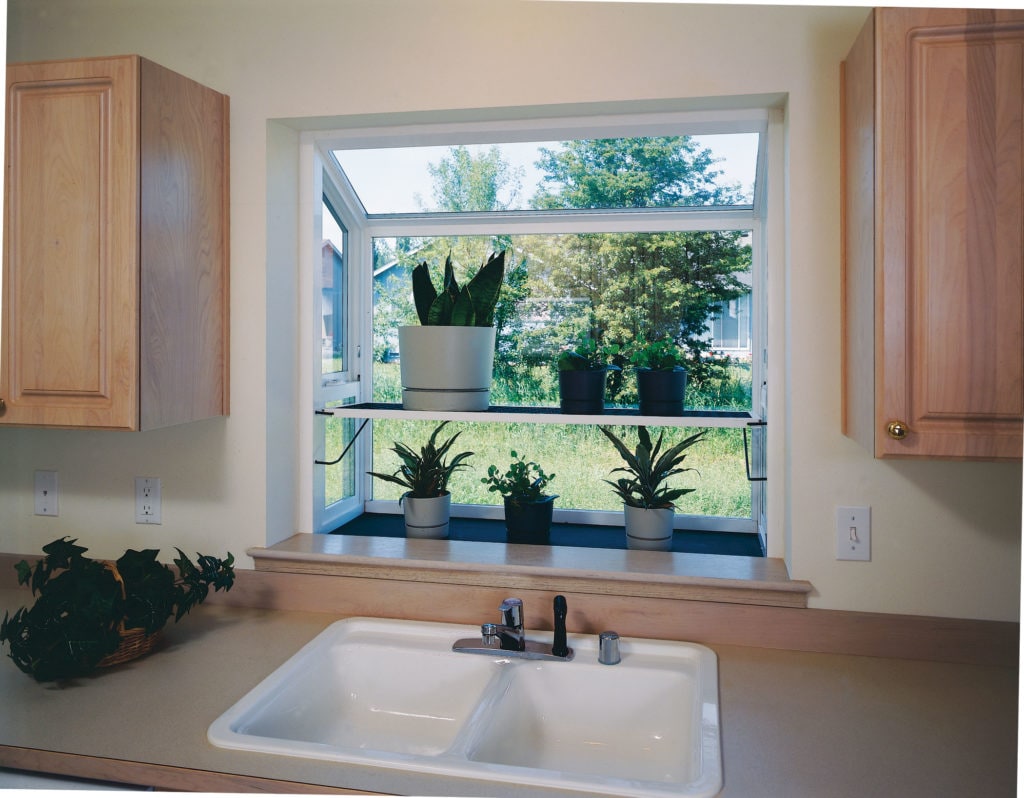 Plants sit on garden window sill.