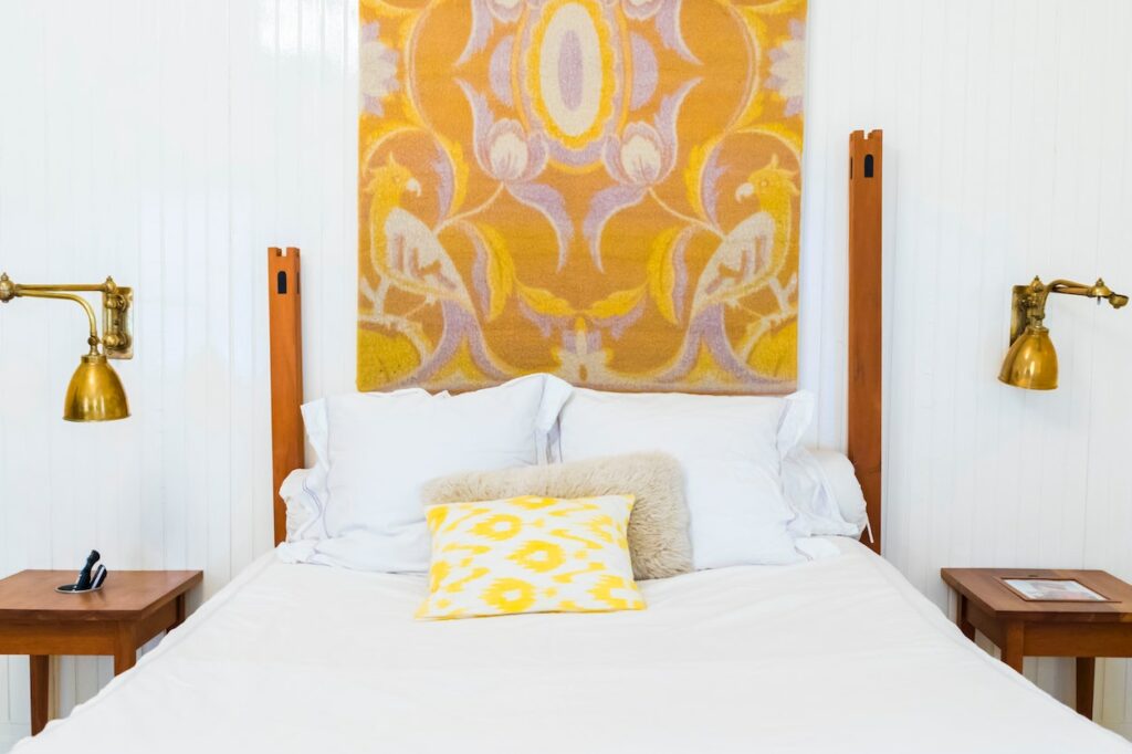 white and yellow bedroom with yellow tapestry above bed