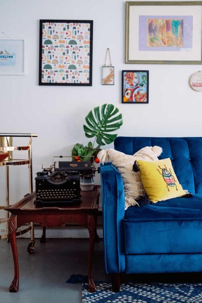 blue velvet couch in living room with colorful decor